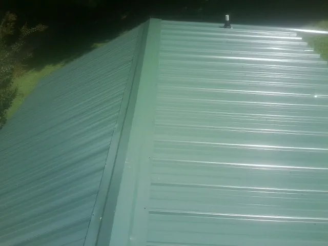 New green metal panels meeting at the ridge of a roof — Flat Roof Repair work by our crew in Wayzata
