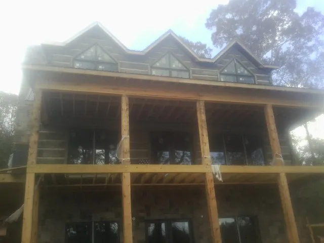 Dormers and porch framing on a large log home under construction — Roof Coating work by our crew in Wayzata
