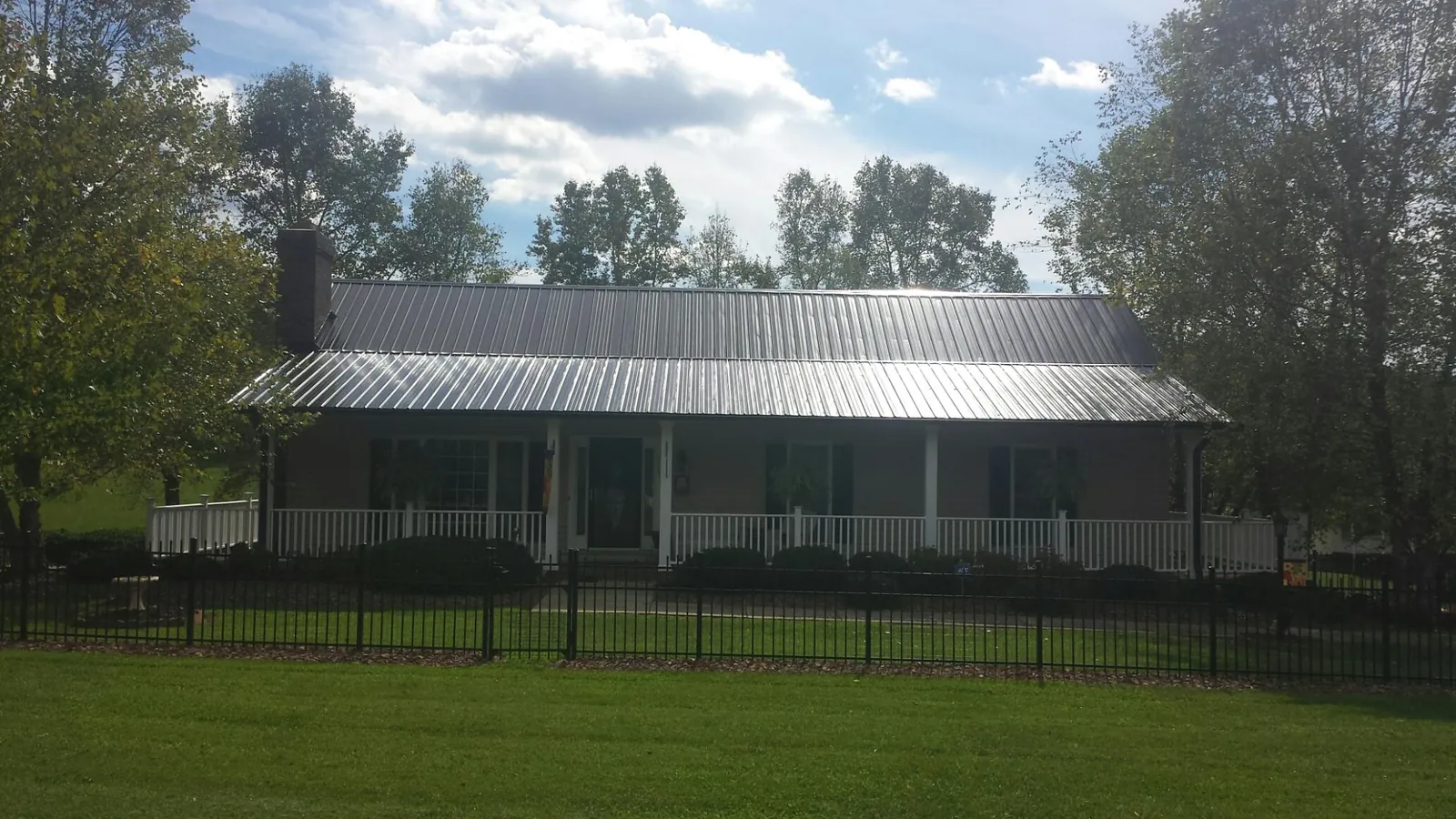 Gray metal roof on a brick ranch with a full width front porch — Gutter Guard Installation work by our crew in Wayzata