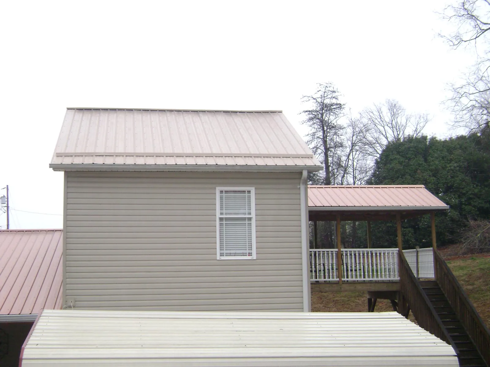 Tan metal roofs on a two story addition and attached porch, from a Roof Replacement job in Wayzata