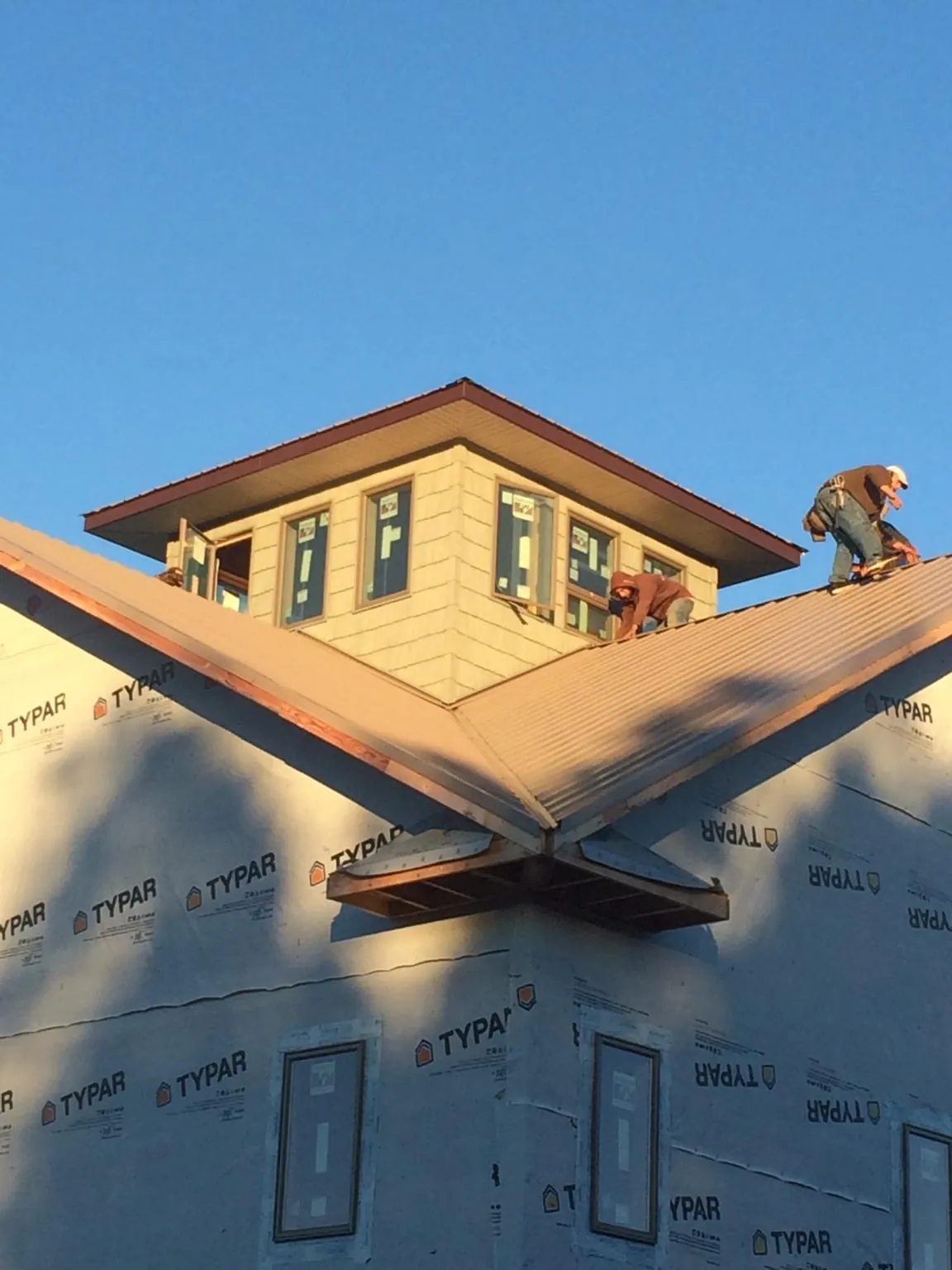 Roofers working around a rooftop cupola on a new metal roof at sunset — Roof Waterproofing in Wayzata by Roofing Brothers
